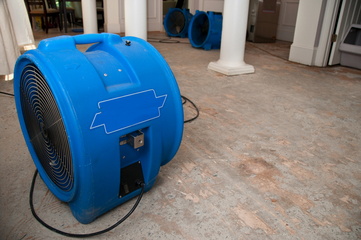 Large air mover drying a floor during the water damage mitigation process